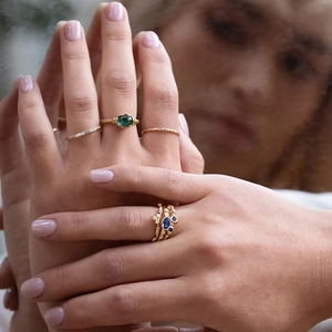 Close-up of gold S925 sterling silver opal and diamond rings worn by a model