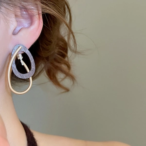 Détail de boucles d'oreilles doubles avec anneaux en métal gris texturé et doré
