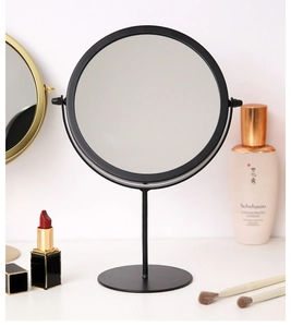 Close-up of minimalist black iron desk mirror with smooth round metal frame and base