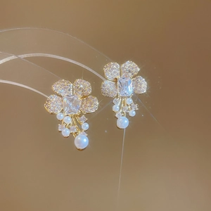 Detail of flower stud earrings with shimmering zircon petals and elegant pearl tassels