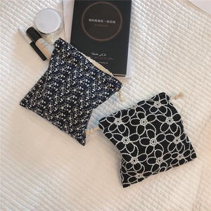 Detail shot of two black cotton drawstring pouches with intricate white lace embroidery