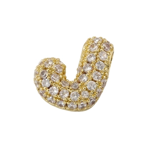 Macro shot of gold-plated letter J pendant pavé set with sparkling cubic zirconia stones