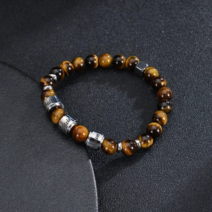 Macro detail of custom engraved metal cylinder and brown tiger eye beads on men's bracelet
