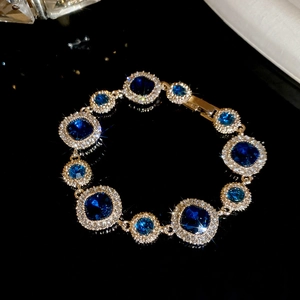 Makroaufnahme von vergoldetem Armband mit blauen Kristallen und funkelndem Zirkonia-Rand