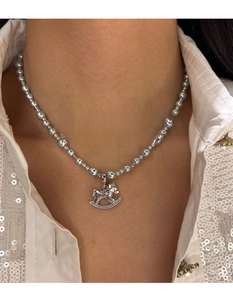 Close-up of a silver rocking horse pendant with pearls and crystals on a necklace
