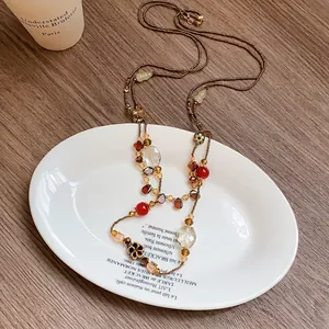 Vintage floral crystal pendant necklace with bronze beads on elegant white ceramic plate