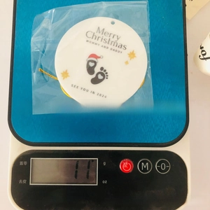Close-up of a circular Christmas ornament showing the 11g weight on a digital scale