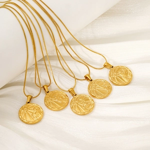 Macro shot of five gold zodiac coin pendants on snake chains over white silk