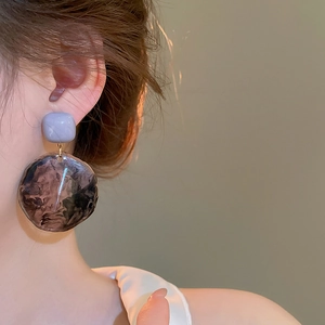 Close-up of geometric earrings with purple marble texture resin and square studs