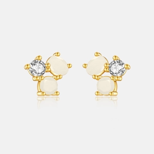 Macro shot of gold-plated cluster earrings with milky white stones and clear zirconias
