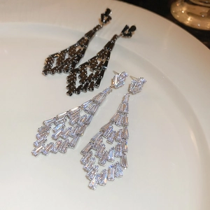 Detail of luxury geometric tassel earrings with zircon pave on white ceramic plate