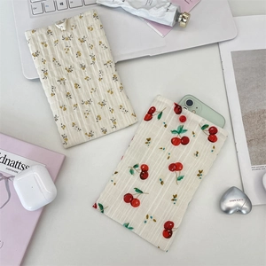 Gros plan de pochettes de téléphone en tissu à fleurs et cerises sur un bureau chic