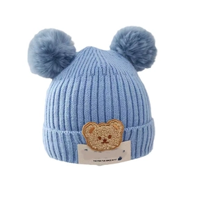 Cute light blue knitted baby hat with dual pom-poms and cartoon bear patch for winter warm