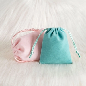 Close-up of plush velvet drawstring bags in pink and mint green for jewelry storage