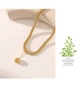 Detail of 14K gold mesh chain necklace with two spherical pendants on stone texture