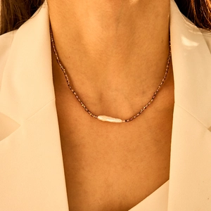 Vue détaillée du collier avec perles violettes et perle baroque portée par un modèle