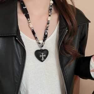 Detail of vintage leopard scarf necklace with heart pendant and silver cross accent