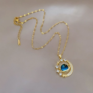 Detailed macro view of planet and moon pendant necklace with blue stone and white zircons