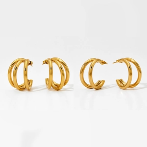 Détails macro des boucles d'oreilles créoles dorées à plusieurs couches au fini poli miroir