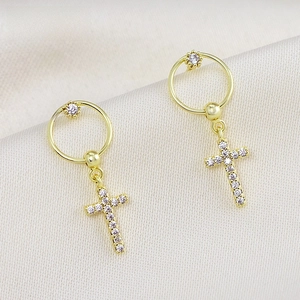 Detalle de aretes de aro chapados en oro de 18K con colgantes de cruz de circonitas