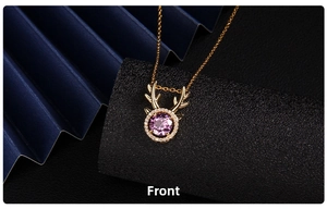 Detail of a gold elk pendant featuring a large purple gemstone and pavé-set crystals