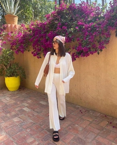 Detail of white pleated long sleeve top and wide leg pants set on a female model