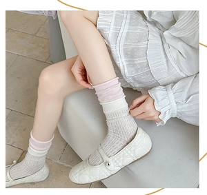 Close-up of white and pink knit slouch socks with ribbed cuffs and hollow patterns