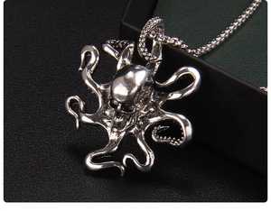 Close-up of hip-hop silver octopus skull pendant on dark leather texture surface