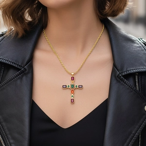 Dettaglio ravvicinato di una collana placcata oro con pendente a croce in zirconi colorati su modella