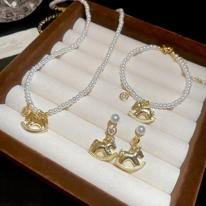 Detail shot of pearl jewelry set with golden horse pendants in a velvet case