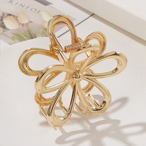 Pince à cheveux fleur évidée en métal doré élégante sur fond blanc minimaliste