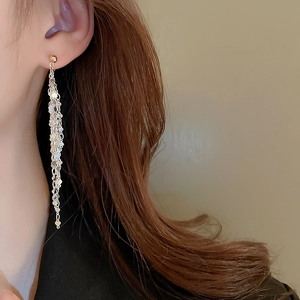Close-up of elegant gold and silver multi-layer tassel earrings worn by a model