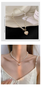 Detail view of pearl necklace with gold OT buckle and heart pendant worn by model
