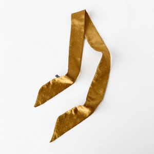 Nahaufnahme eines goldenen Satin-Schals mit silbernen Punkten und Markenetikett