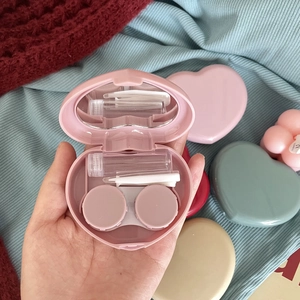 Detailed interior view of heart-shaped contact lens case with pink shell and tools