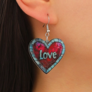 Close-up of heart-shaped acrylic earring with Love text and stained glass pattern