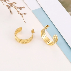 Macro detail of gold-plated C-shape hoop earrings with a triple-layered wheat grain texture
