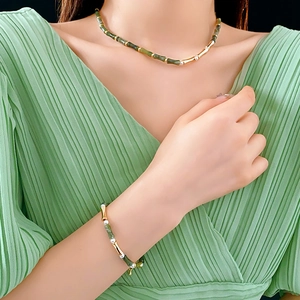 Detailed view of bamboo style jade and pearl necklace set on an elegant green outfit