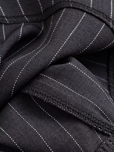 Gros plan sur la texture rayée et les coutures surjetées du pantalon large
