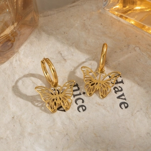 Close-up of elegant gold butterfly hoop earrings on a vintage textured background