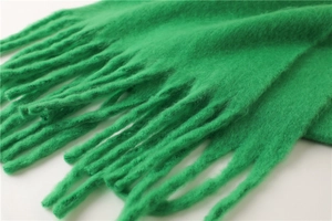 Vue détaillée de la texture pelucheuse épaisse et des franges d'une écharpe verte