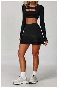 Detail of high-waist pleated tennis skirt and long sleeve cutout crop top in black
