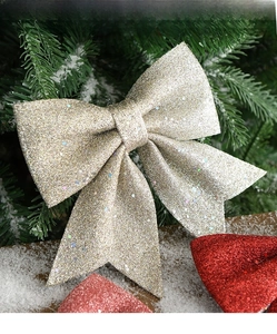 Detail of Christmas bow with shiny metallic sequins on a snowy Christmas tree branch