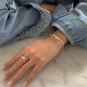 Silver knot ring and matching chain bracelet set shown on model with minimalist aesthetic
