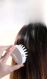 Detail of white silicone scalp massager brush being used on hair for cleansing