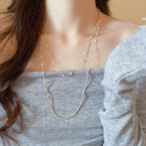 Close-up of double-layer gold snake chain necklace featuring elegant pearl accents on model