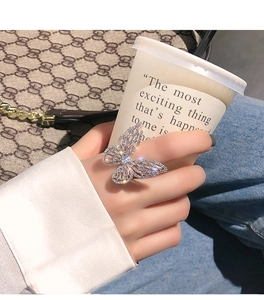 Close-up of sparkling silver butterfly zircon ring worn on finger with casual background