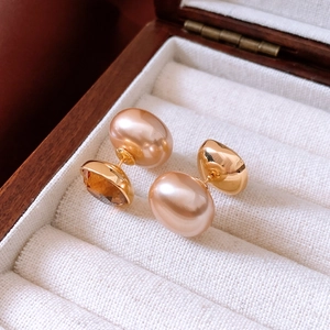 Detail of 18K gold plated pearl earrings with brown crystal inlay in a jewelry box