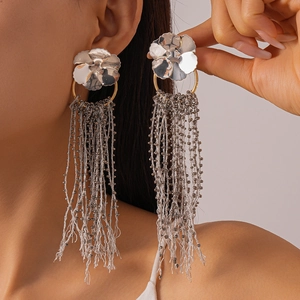 Detailed view of silver metal flower earrings with long grey beaded tassels on model