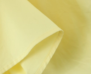 Gros plan sur la texture du tissu jaune et les détails de couture plissée de la robe